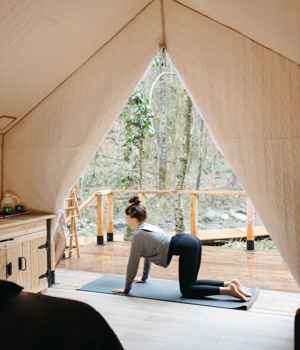 A serene woman in activewear stretching indoors in a calm setting.